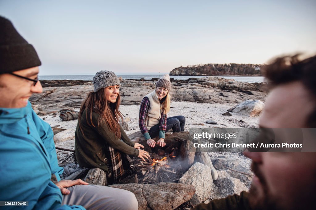 Friends relaxing around campfire, Portland, Maine, USA