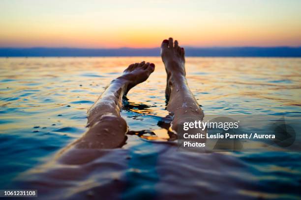 feet of woman floating in dead sea at sunset, madaba governorate, jordan - dead sea float stock pictures, royalty-free photos & images