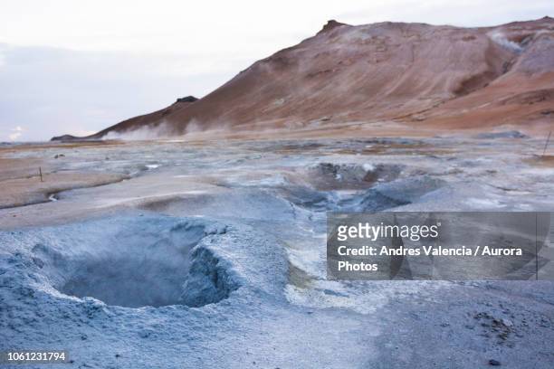 boiling hot blue coloured mud puddle with namafjall in the background, at hverarâândor hverir geothermal area, at namaskard pass in iceland. - fire and brimstone stock-fotos und bilder