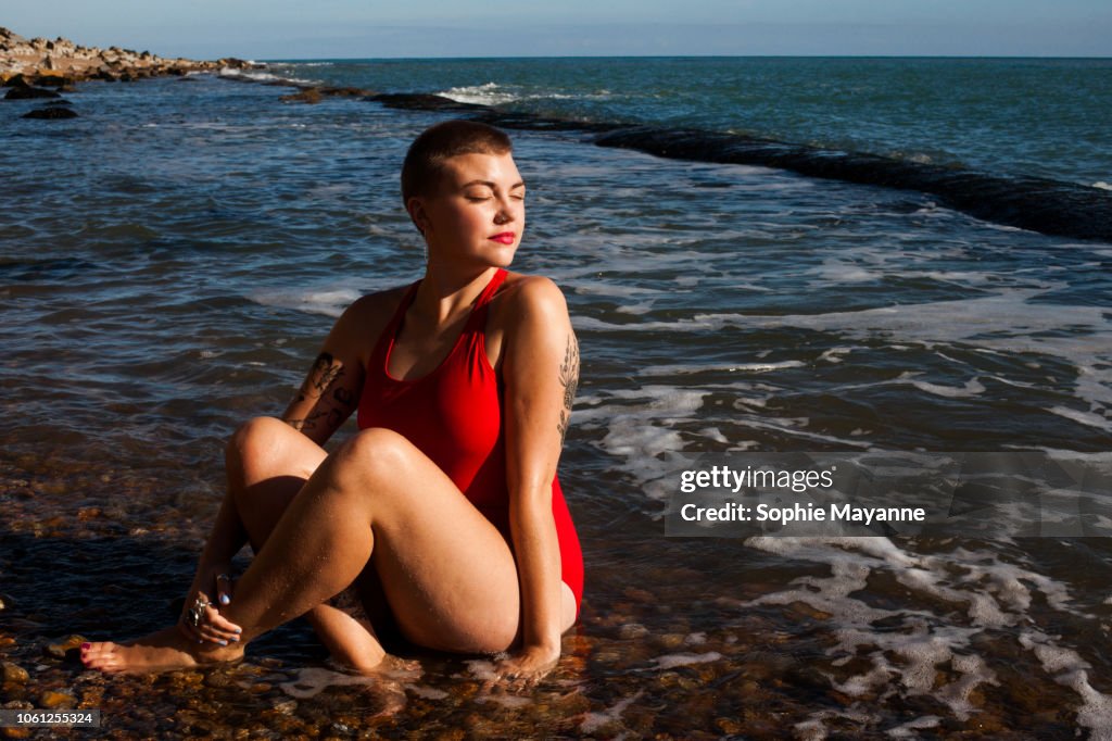 A young woman sat in the sea looking over her shoulder