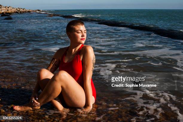 A young woman sat in the sea looking over her shoulder