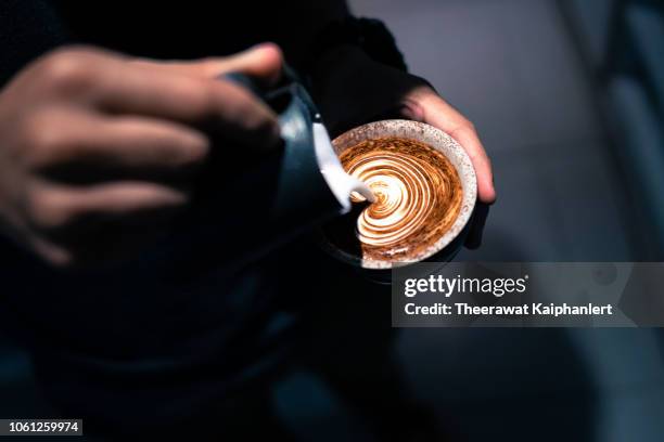 close up of hand pouring coffee latte art - latte art ストックフォトと画像