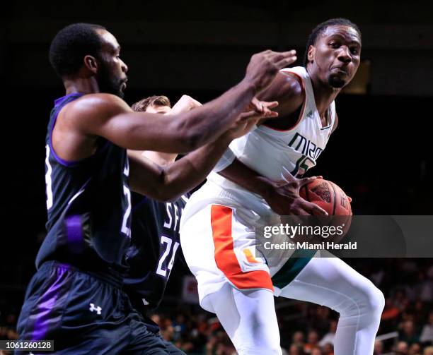 Miami's Ebuka Izundu looks to pass around Stephen F. Austin's Samuli Nieminen and Nathan Bain in the first half at Watsco Center in Coral Gables,...