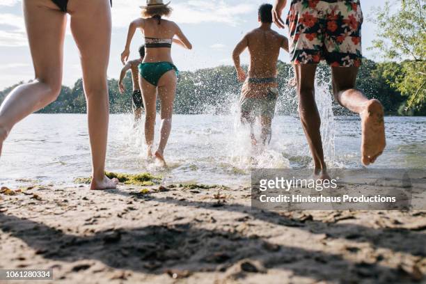group of friends running into lake together - beautiful asian legs - fotografias e filmes do acervo
