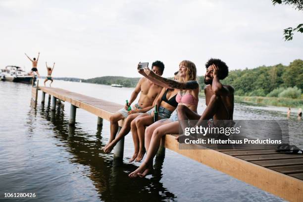 friends taking selfie on lake pier - lake stock photos et images de collection