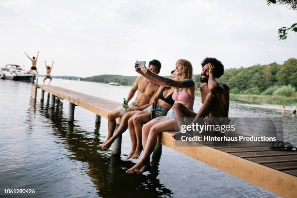 friends taking selfie on lake pier - berlin summer stockfoto's en -beelden