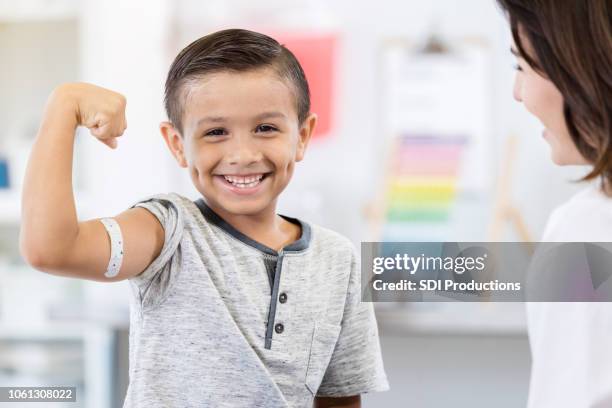 niño valiente muestra vendaje de brazo en el pediatra - cute nurses fotografías e imágenes de stock