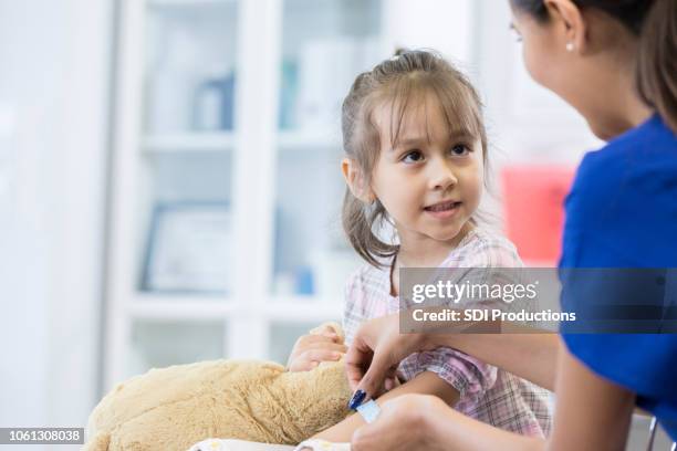 little girl receives band-aid from pediatrician - applying bandage stock pictures, royalty-free photos & images