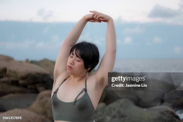 peaceful woman stretching with eyes closed and armpit hair - armpit hair woman stock pictures, royalty-free photos & images