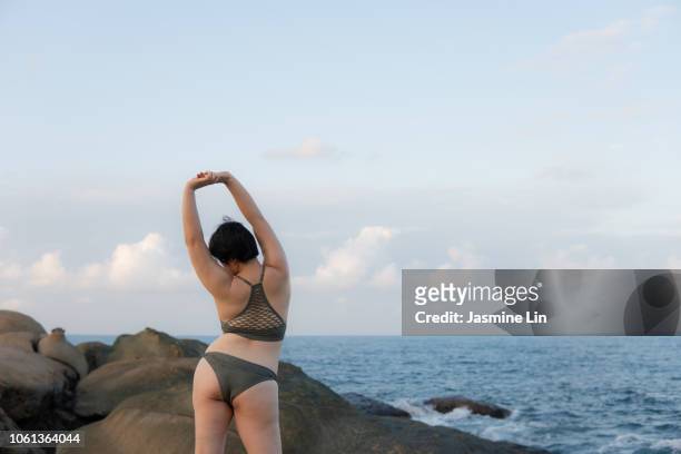 rear view of carefree woman stretching by the beach - showus skin stock pictures, royalty-free photos & images