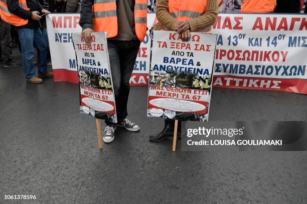 Municipal workers hold placards reading messages against the retirement age as they take part in a rally in central Athens, on November 14 during a...