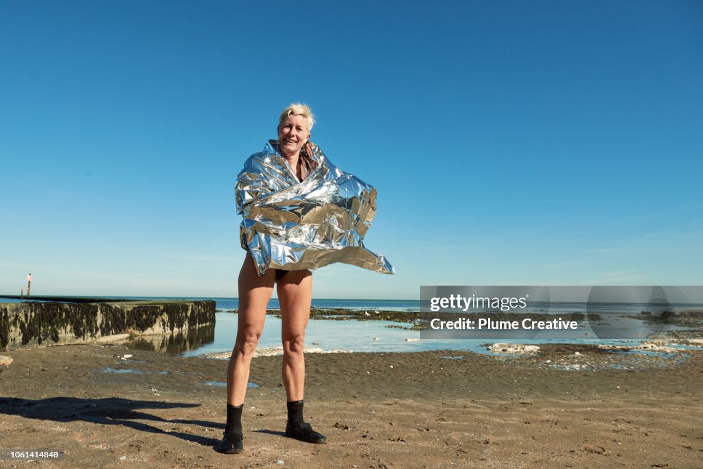 Portrait of woman wrapped in foil blanket after a swim in the sea