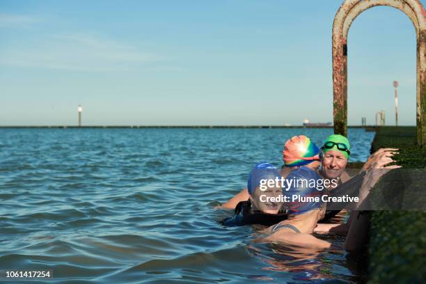 group of women taking a break from swim in tidal pool - sea club ストックフォトと画像