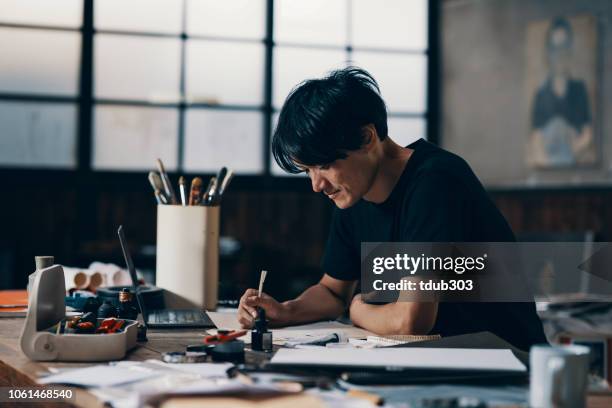 中高年の男性アーティストが彼のスタジオでアイデアをスケッチ - 芸術家 ストックフォトと画像