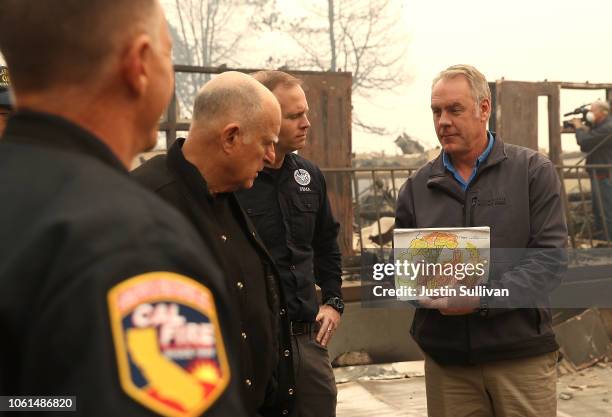 California Governor Jerry Brown and FEMA Adminstrator Brock Long look on as U.S. Secretary of the Interior Ryan Zinke holds up a child's school work...