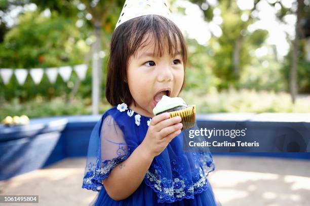 little girl eating a birthday cupcake - cupcakes girls fotografías e imágenes de stock