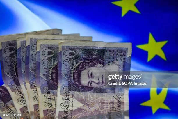 Twenty pounds bank notes are seen with European union flag on the background.