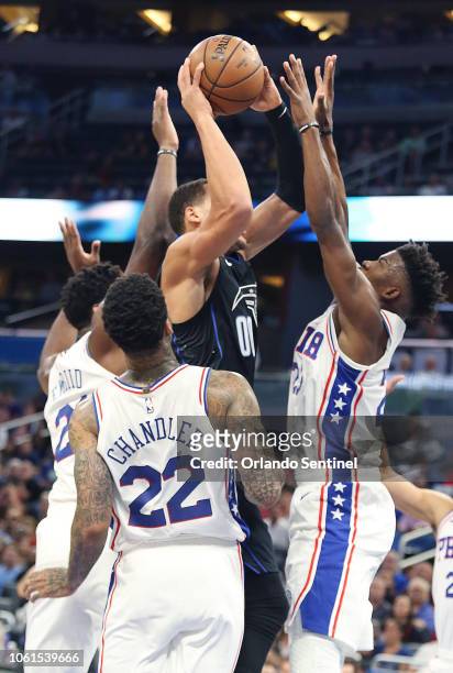 Philadelphia 76ers defenders Joel Embiid, left, Wilson Chandler and Jimmy Butler, right, swarm the Orlando Magic's Aaron Gordon at the Amway Center...