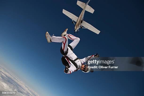 man is diving out of the plane in a sit position. - paracaídas fotografías e imágenes de stock