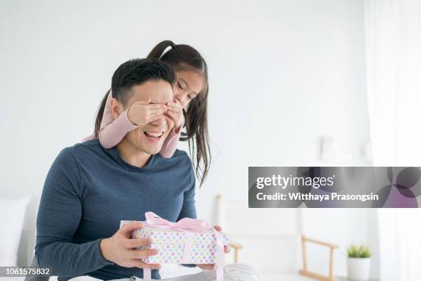 happy father's day! child daughter congratulating dad and giving him gift box. daddy and girl smiling and hugging. family holiday and togetherness. - child giving gift stock-fotos und bilder