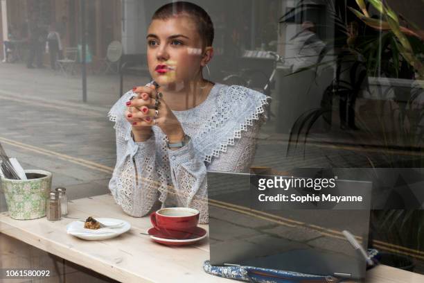 A young woman sat in a coffee shop looking out of the window