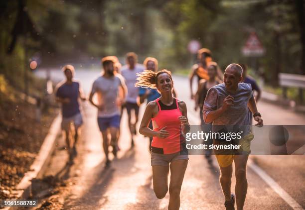 happy mid adult couple running a marathon race on the road. - large group of people running stock pictures, royalty-free photos & images