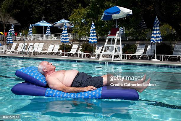 senior man floating on raft in pool - pool raft stock pictures, royalty-free photos & images