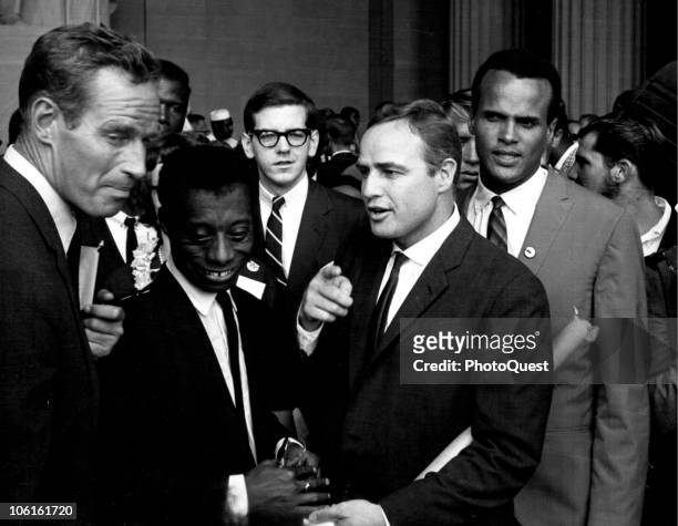 Framed by American actor Charleton Heston and singer Harry Belafonte , writer James Baldwin talks with actor Marlon Brando in the Lincoln Memorial...