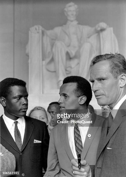 American actor Sidney Poitier listens to singer Harry Belafonte as actor Charleton Heston stands with them in the Lincoln Memorial during the March...