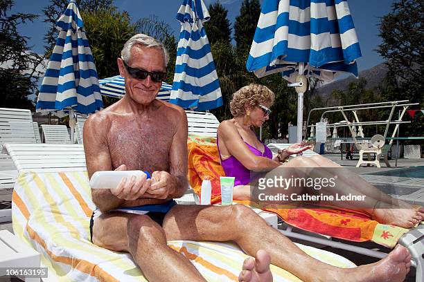 senior man putting sunscreen on poolside. - putting lotion stock pictures, royalty-free photos & images