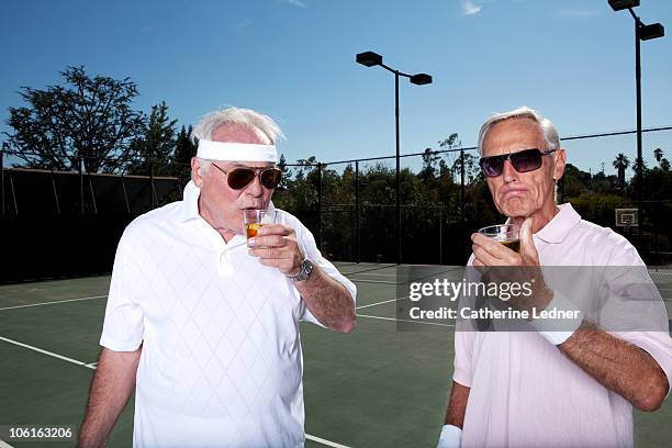 two senior men drinking scotch on the tennis court - tennis stock-fotos und bilder