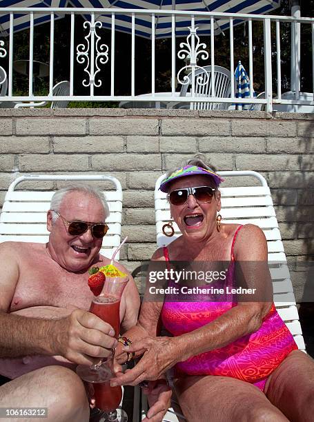senior couple enjoying drinks while sunbathing. - 80s swimwear stock pictures, royalty-free photos & images