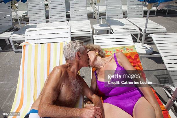 Portrait of senior couple kissing on lounge chairs