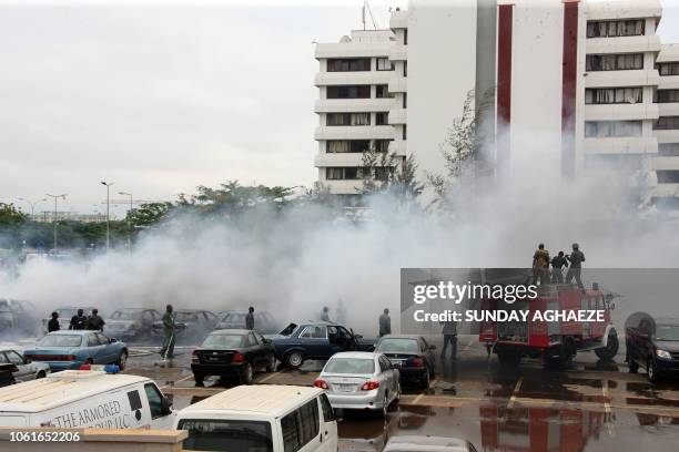 Firefighters try to extinguish a fire after a bomb blast at the parking lot of police headquaters in Abuja on June 16, 2011. The bomb killed two...