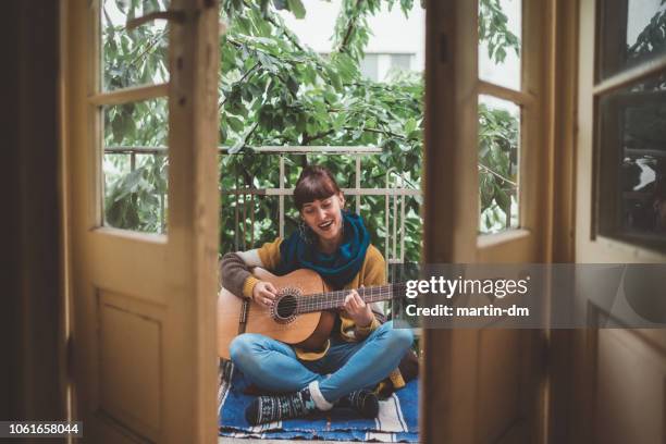 hippie woman playing the guitar at home - martin guitar stock pictures, royalty-free photos & images