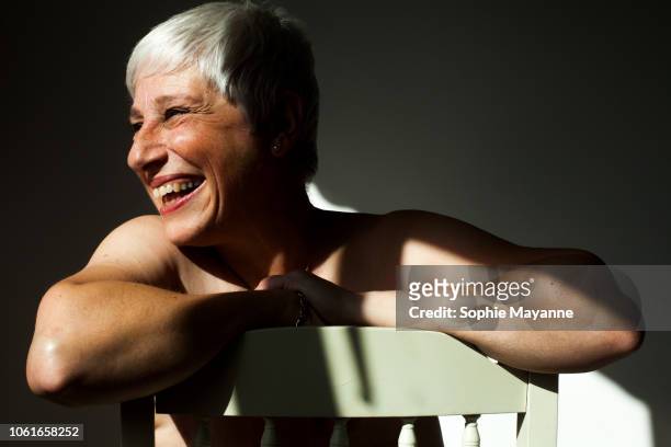 A mature woman leaning on the back of a chair in the sunlight