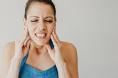 Annoyed young woman suffering from toothache and touching jaw
