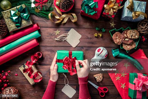 top view of woman hands placing tied bow on gift box. christmas themes. - sweet charity stock pictures, royalty-free photos & images