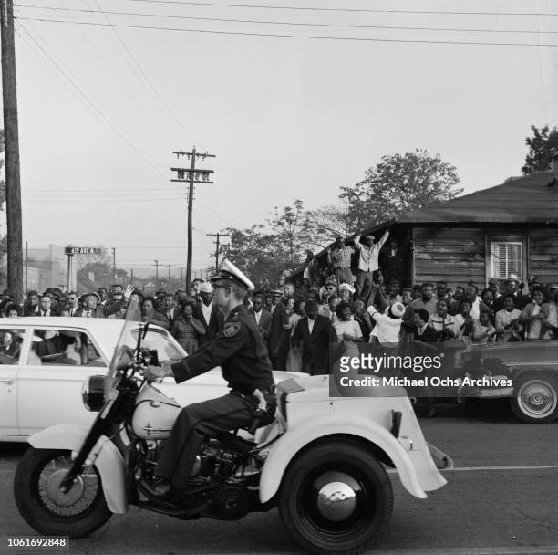Police officer drives past protestors on 6th Avenue North during the Birmingham Campaign in Birmingham, Alabama, May 1963. The movement, which called...
