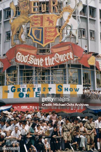Procession in Hong Kong to celebrate the coronation of Queen Elizabeth II in London, June 1953. A hoarding reading 'God Save the Queen' has been...
