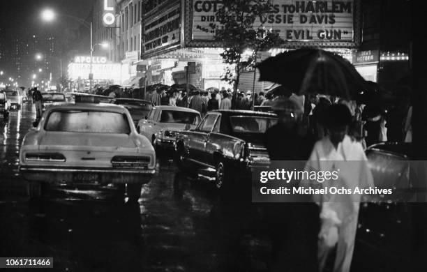 People queuing in the rain for an Isaac Hayes concert at the Apollo Theater on West 125th Street, New York City, 26th June 1970. The cinema in the...