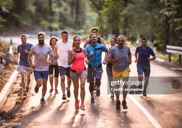 full length of marathon runners having a race through nature. - road running stock pictures, royalty-free photos & images