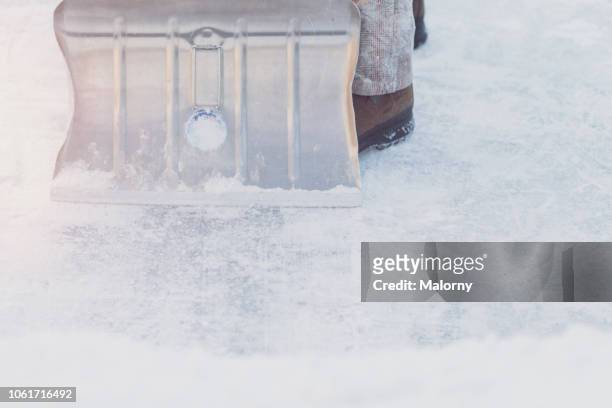 close-up of a man shoveling snow with a snow shovel standing on ice. winter. - snow shovel stock-fotos und bilder