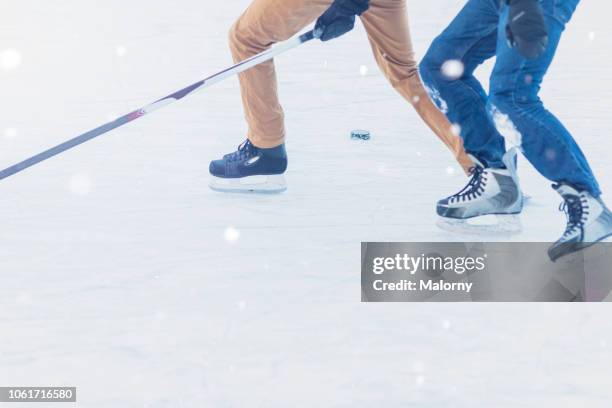 close-up of two people skating and playing ice hockey. light snowfall - hockey rink stock-fotos und bilder
