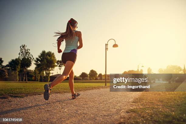 tienermeisje joggen in stadspark - hardlopen stockfoto's en -beelden