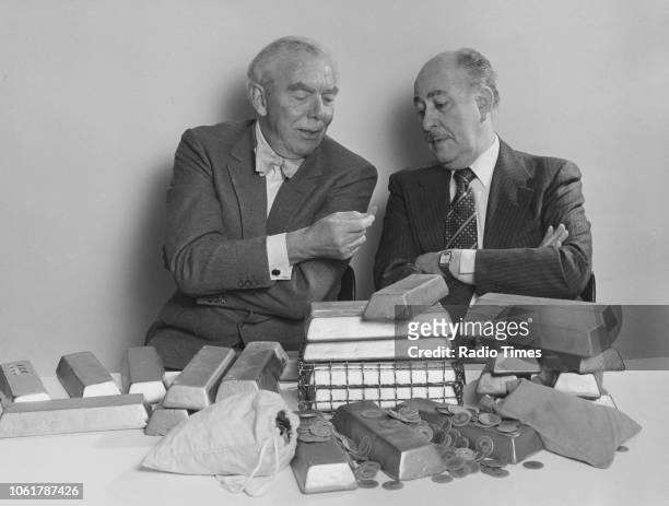 Writer Frank Muir and actor Alfred Marks pictured inspecting gold bars, photographed for Radio Times in connection with the BBC Radio 4 series 'Frank...