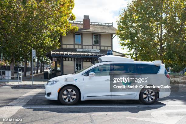 Close-up of self driving minivan, with LIDAR and other sensor units and logo visible, part of Google parent company Alphabet Inc, driving past...