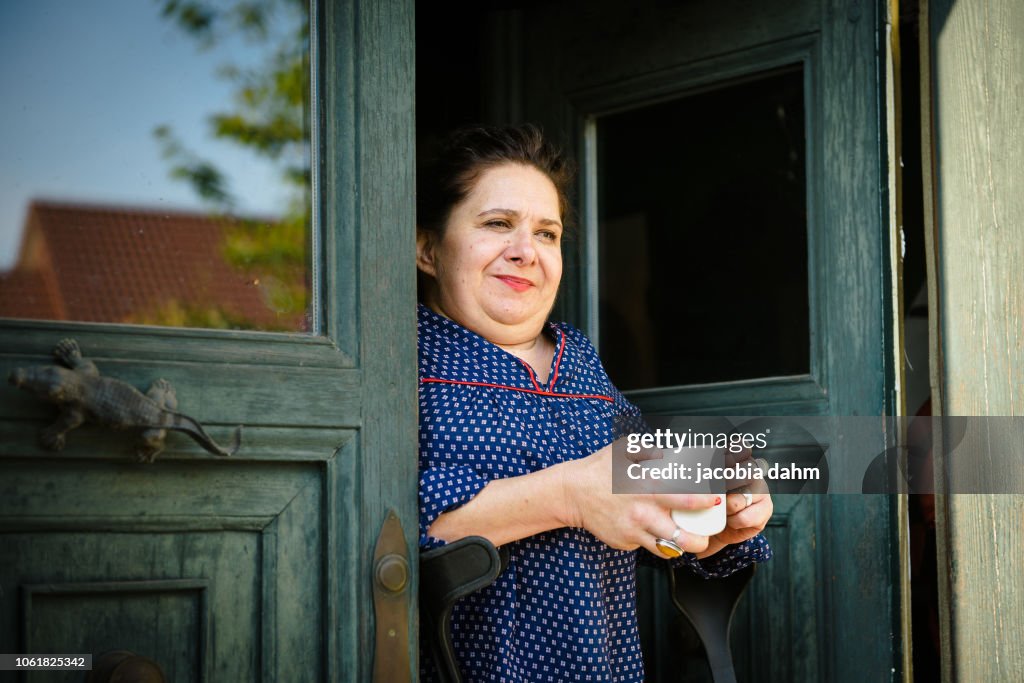 Woman standing in doorway of her home, looking out
