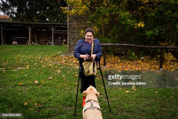 Woman outdoors, with crutches, and dog