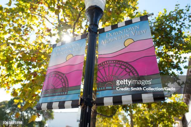 Low-angle view of sign for downtown Mountain View, with sun and trees visible in the background, in the Silicon Valley town of Mountain View,...
